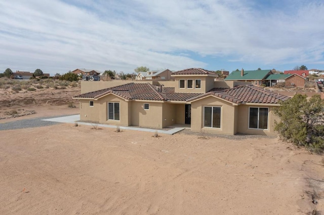 rear view of house featuring a tile roof, stucco siding, and a residential view
