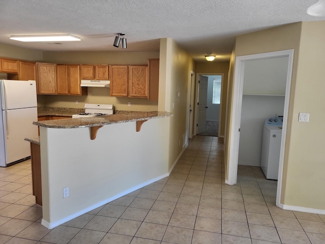 1511 White Pine Dr, Rio Rancho, NM 87144 - kitchen with white appliances, washer / dryer, light tile patterned flooring, under cabinet range hood, and a textured ceiling