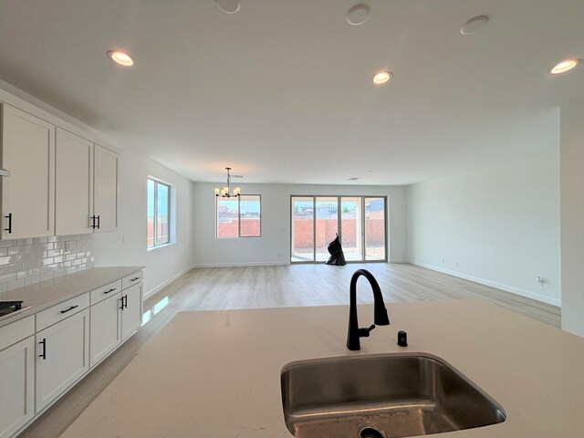 3225 Matador St SE, Rio Rancho, NM 87144 - kitchen featuring recessed lighting, a chandelier, light wood-style flooring, tasteful backsplash, and white cabinetry