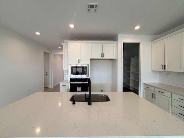 3225 Matador St SE, Rio Rancho, NM 87144 - kitchen featuring stainless steel microwave, oven, recessed lighting, tasteful backsplash, and light stone counters