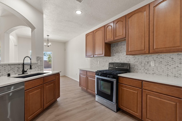 1941 Platina Rd SE, Rio Rancho, NM 87124 - kitchen featuring stainless steel appliances, a sink, light wood-type flooring, backsplash, and brown cabinetry