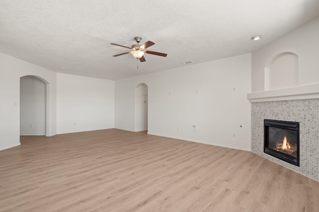 1941 Platina Rd SE, Rio Rancho, NM 87124 - unfurnished living room with light wood-style floors, a tiled fireplace, a textured ceiling, and a ceiling fan