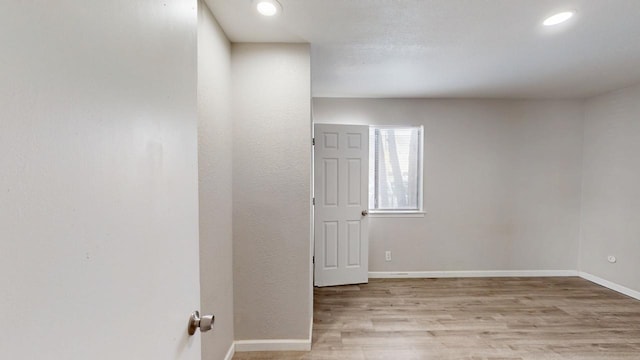 unfurnished room featuring baseboards, wood finished floors, and recessed lighting
