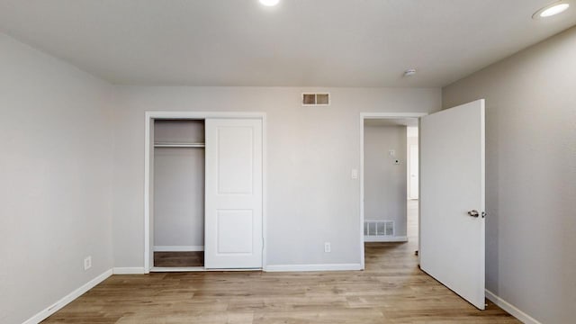 unfurnished bedroom with baseboards, light wood finished floors, and visible vents