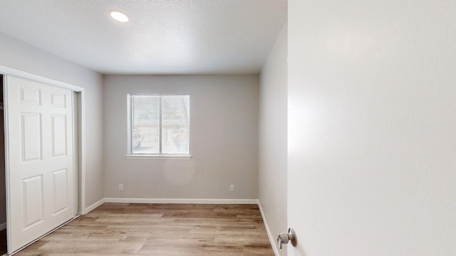 unfurnished bedroom with recessed lighting, a closet, light wood finished floors, and baseboards