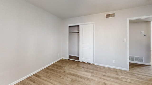 unfurnished bedroom with baseboards, visible vents, light wood-style floors, and a closet