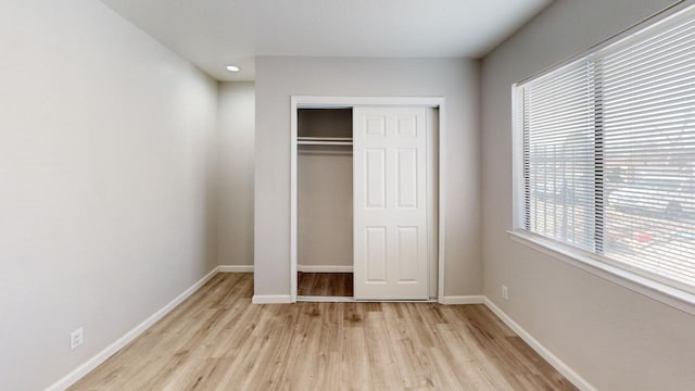 unfurnished bedroom featuring a closet, light wood finished floors, and baseboards