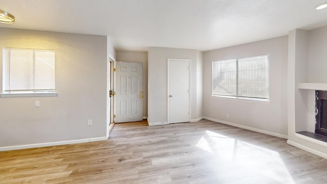 unfurnished living room with light wood finished floors and baseboards