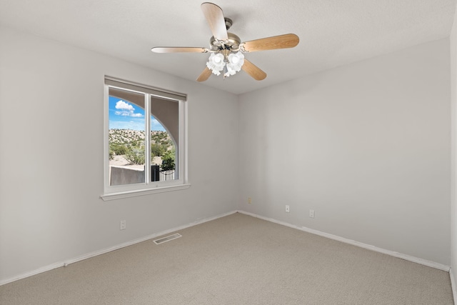 empty room with carpet, ceiling fan, and baseboards
