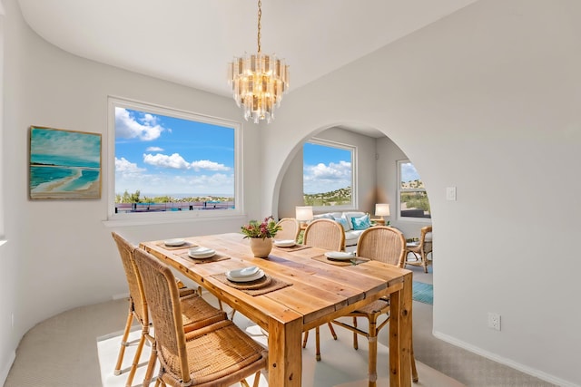 dining space with a chandelier, carpet floors, and arched walkways