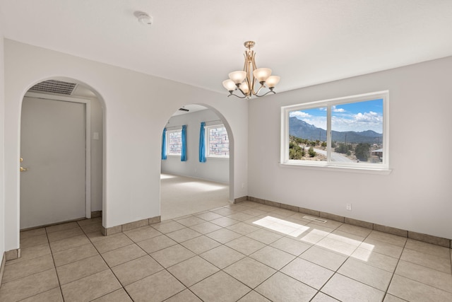 unfurnished room with a chandelier, plenty of natural light, arched walkways, and a smoke detector
