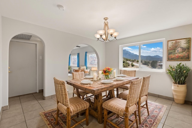 dining space with a chandelier, plenty of natural light, arched walkways, and light tile patterned floors