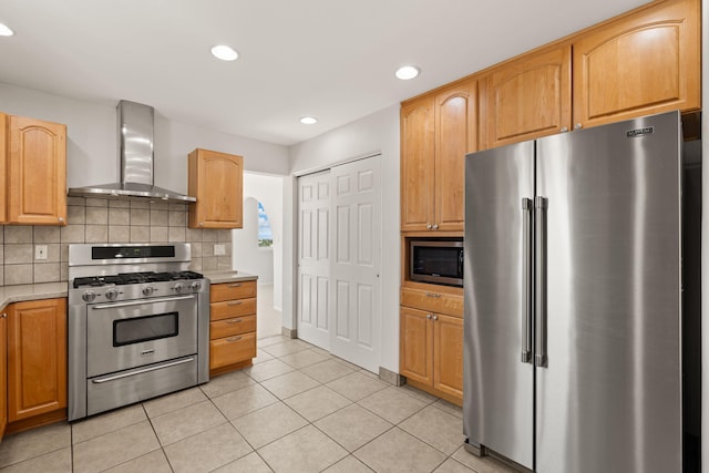 kitchen with appliances with stainless steel finishes, wall chimney range hood, light tile patterned flooring, recessed lighting, and backsplash