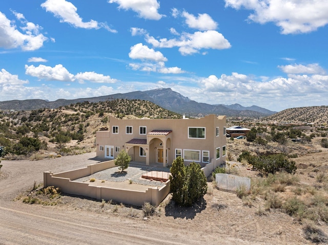 view of front of house featuring a mountain view, stucco siding, fence, a tile roof, and driveway