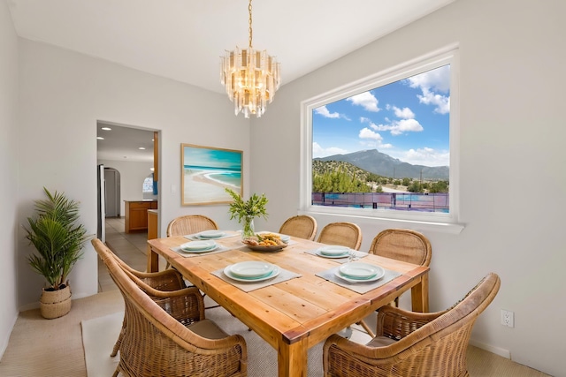 dining space with a chandelier, carpet flooring, a mountain view, arched walkways, and baseboards