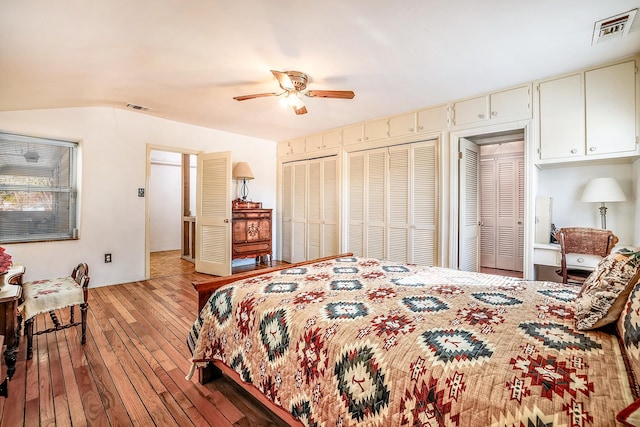 bedroom featuring a ceiling fan, multiple closets, visible vents, and light wood-style flooring