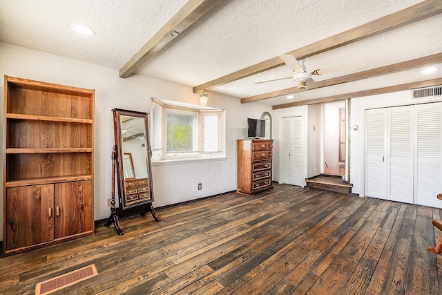 unfurnished bedroom with dark wood-type flooring, a textured ceiling, beam ceiling, and visible vents