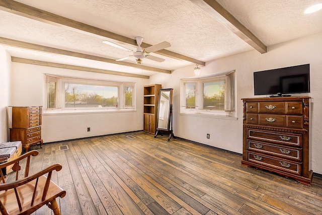 sitting room with wood-type flooring, a textured ceiling, plenty of natural light, and beam ceiling