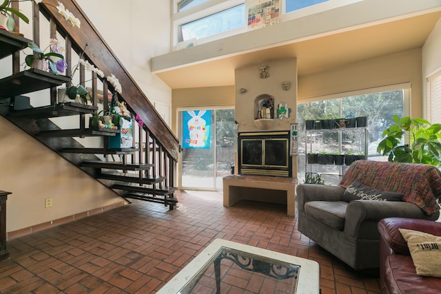 32 Puntilla Dr Unit B, Tijeras, NM 87059 - living room featuring brick floor, a glass covered fireplace, a towering ceiling, and stairs
