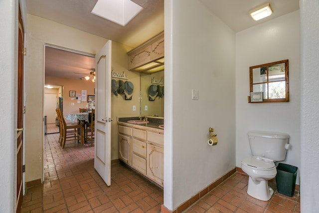 32 Puntilla Dr Unit B, Tijeras, NM 87059 - bathroom with brick floor, a skylight, vanity, baseboards, and toilet