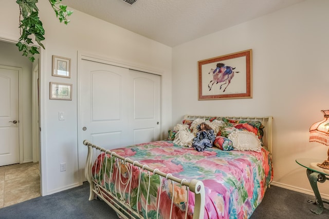 carpeted bedroom with a textured ceiling, a closet, and baseboards
