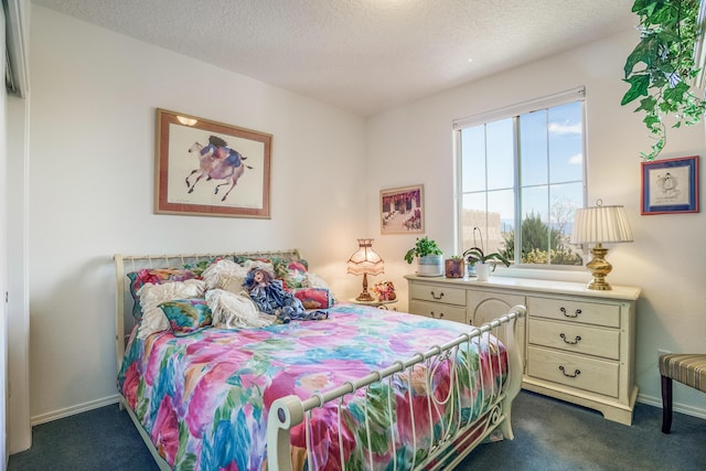 bedroom with a textured ceiling, dark colored carpet, and baseboards