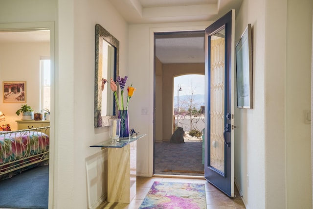 foyer entrance with light tile patterned floors and light colored carpet