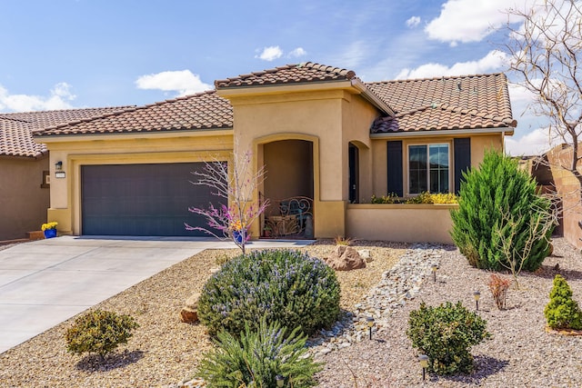 mediterranean / spanish-style home featuring a garage, driveway, a tiled roof, and stucco siding