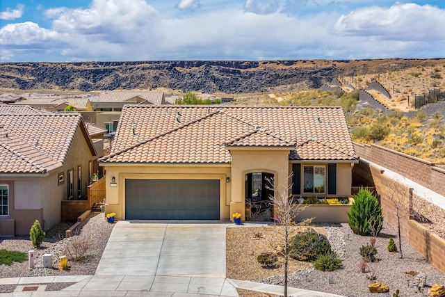 mediterranean / spanish-style home with concrete driveway, stucco siding, a tile roof, a garage, and fence