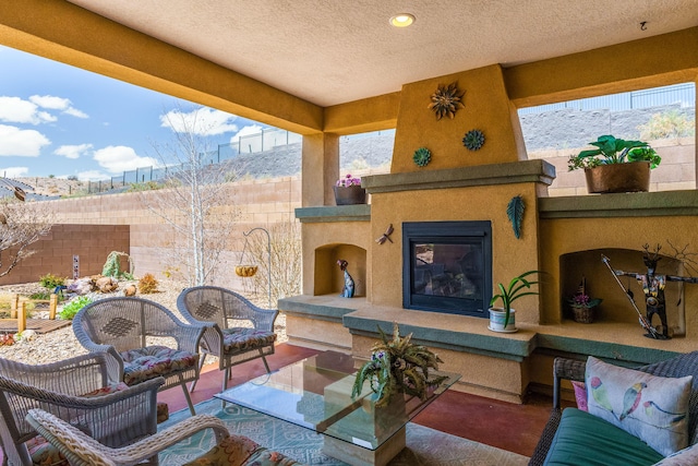 view of patio with an outdoor living space with a fireplace and fence