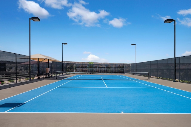view of tennis court with community basketball court and fence