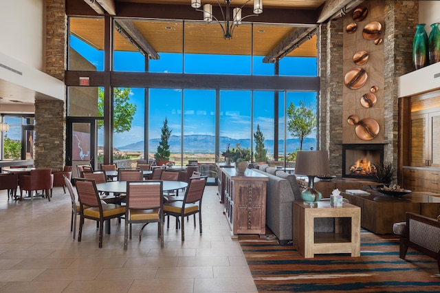 dining space featuring a towering ceiling, a mountain view, a fireplace, beamed ceiling, and wood ceiling