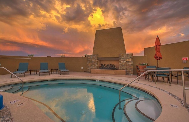 pool featuring a patio area and an outdoor stone fireplace