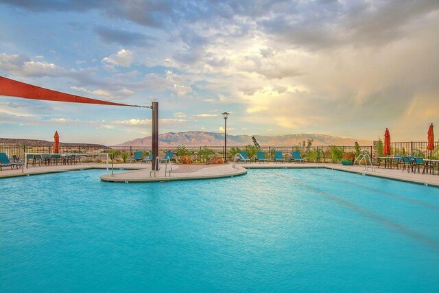 community pool featuring a patio, a mountain view, and fence