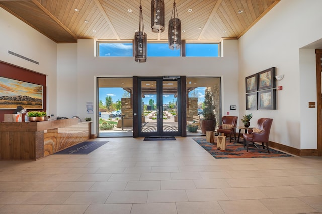 foyer featuring a towering ceiling, baseboards, wooden ceiling, and a healthy amount of sunlight