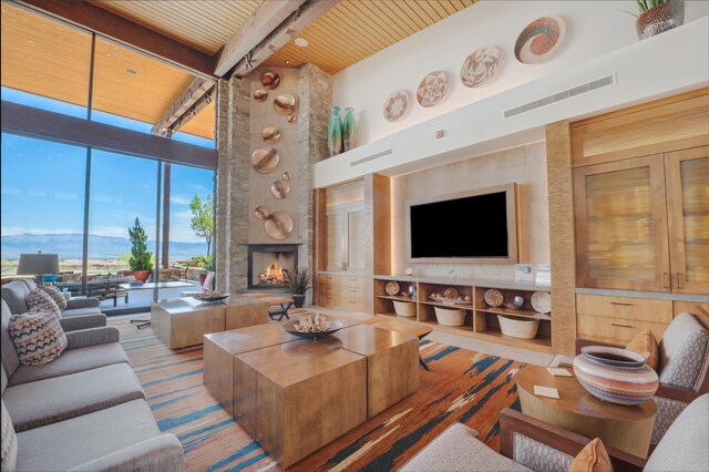 living room featuring a towering ceiling, a fireplace, beamed ceiling, a wall of windows, and wood ceiling