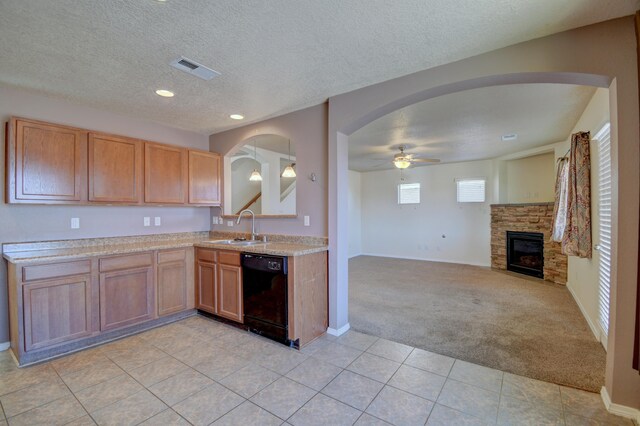6259 Azaleas Rd NW, Albuquerque, NM 87114 - kitchen with black dishwasher, light carpet, light countertops, a stone fireplace, and light tile patterned floors