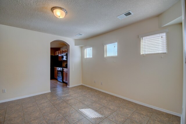 6259 Azaleas Rd NW, Albuquerque, NM 87114 - unfurnished room featuring arched walkways, a textured ceiling, and tile patterned flooring