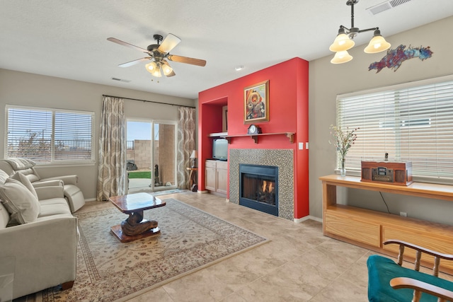 tiled living room with a ceiling fan, baseboards, visible vents, and a tiled fireplace