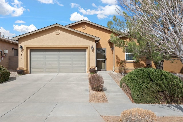 view of front of property with stucco siding, an attached garage, and driveway