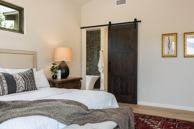 1016 Guadalupe Villa NW, Albuquerque, NM 87114 - bedroom featuring visible vents, baseboards, a barn door, and wood finished floors