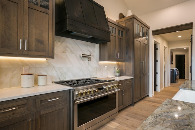 1016 Guadalupe Villa NW, Albuquerque, NM 87114 - kitchen featuring range with two ovens, premium range hood, decorative backsplash, and dark brown cabinetry