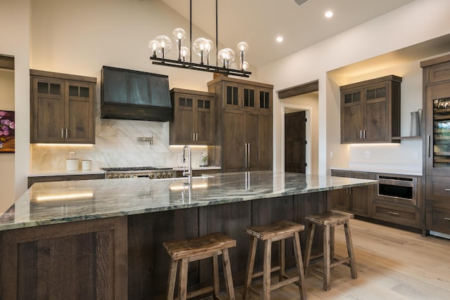 1016 Guadalupe Villa NW, Albuquerque, NM 87114 - kitchen with dark brown cabinetry, vaulted ceiling, premium range hood, a breakfast bar area, and backsplash