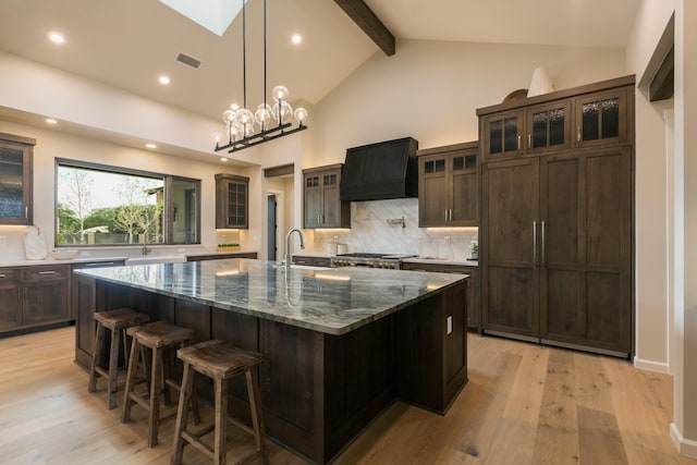 1016 Guadalupe Villa NW, Albuquerque, NM 87114 - kitchen with visible vents, premium range hood, beam ceiling, light wood finished floors, and a large island with sink