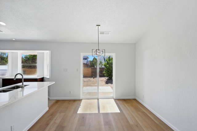 16 Apache Plume Rd, Los Lunas, NM 87031 - unfurnished dining area featuring light wood-style floors, a textured ceiling, and a chandelier