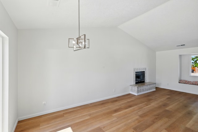 16 Apache Plume Rd, Los Lunas, NM 87031 - unfurnished living room with a tiled fireplace, vaulted ceiling, light wood-style flooring, and a chandelier
