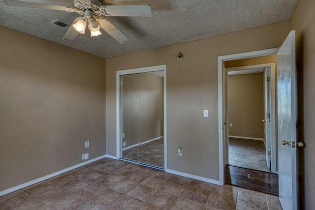unfurnished bedroom featuring a ceiling fan, a textured ceiling, visible vents, baseboards, and a closet