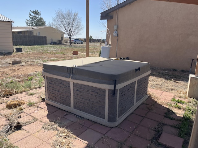 details featuring a hot tub, stucco siding, and fence