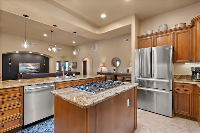 3605 Greystone Ridge Dr SE, Rio Rancho, NM 87124 - kitchen with stainless steel appliances, arched walkways, a sink, brown cabinets, and a center island