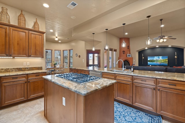 3605 Greystone Ridge Dr SE, Rio Rancho, NM 87124 - kitchen with a sink, stainless steel appliances, a center island, brown cabinetry, and light stone countertops